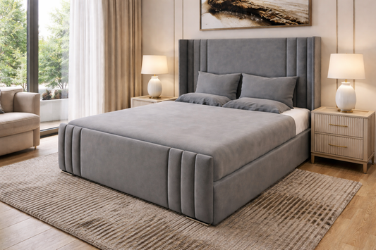 Gray upholstered bed in a bedroom setting with lamps and decor.